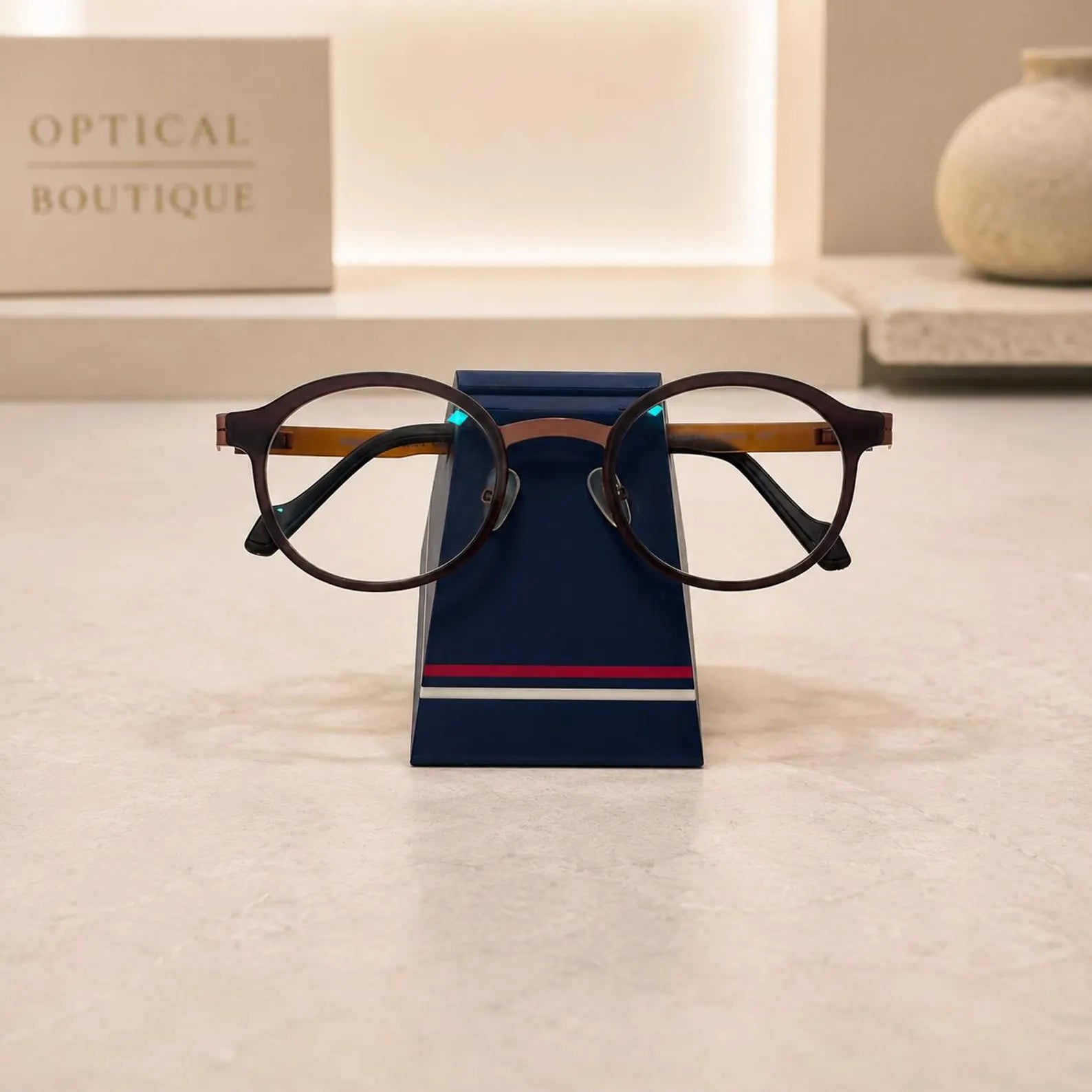 Simple Eyeglass Holder Stand front view — modern trapezoid silhouette in matte navy with red and white racing stripe